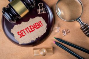 Judge's gavel, magnifying glass and word settlement written on a piece of paper