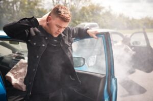 A male motorist experiences pain as he exits his vehicle following a car crash.
