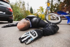 Motorcycle driver without the helmet laying on the road