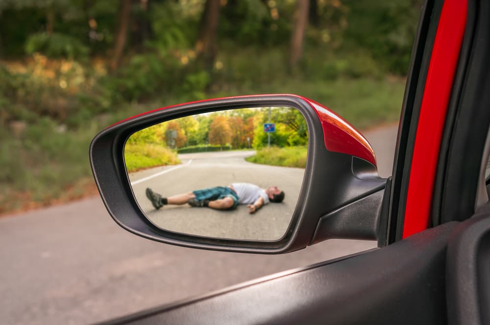 Rearview mirror reflecting a man struck by a car – car accident concept.