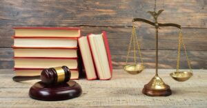 Law concept - Open law book, Judge's gavel, scales, Themis statue on table in a courtroom or law enforcement office. wooden background.