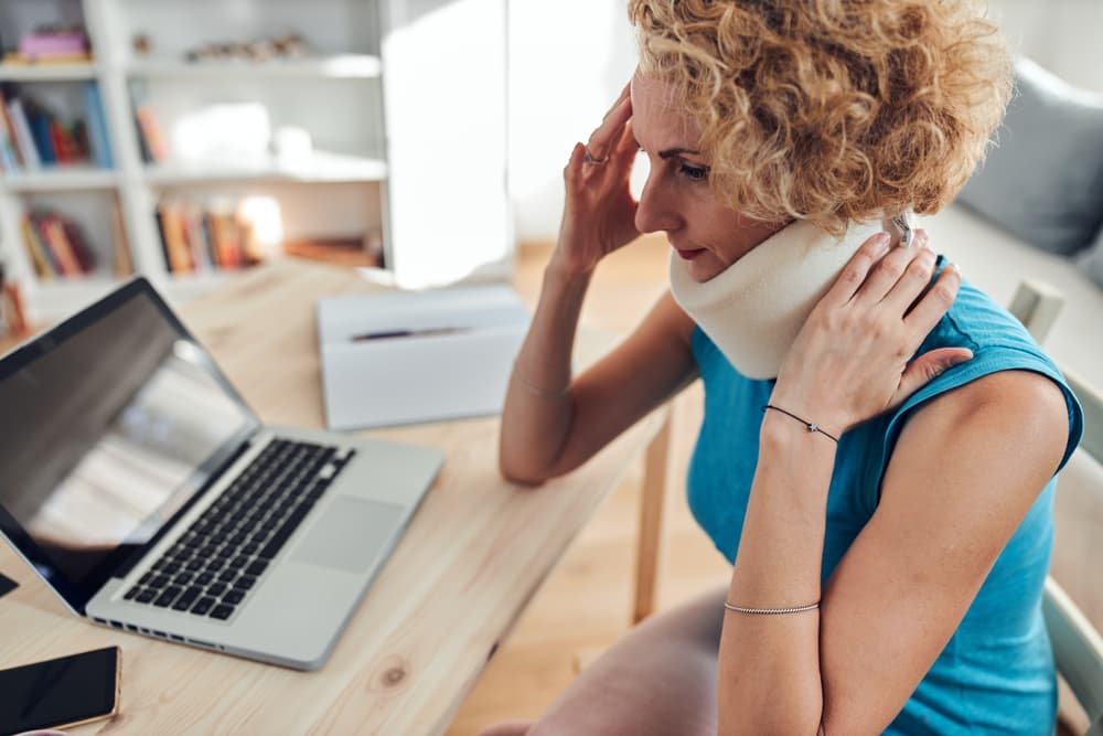 person with neck brace holding head and neck