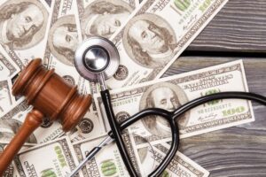 A wooden gavel, stethoscope, and a stack of dollar bills.