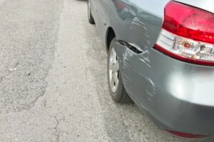 A silver car with minor damages on back side