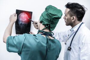 Doctor and surgeon examining x-ray film of patient 's head for brain, skull injury.