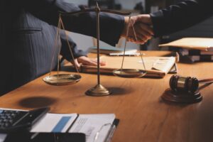 Attractive young lawyer in an office discussing contract papers with colleagues, with brass scales on a wooden desk, symbolizing law, justice, and legal services