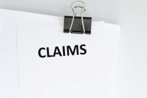"Card with the word 'Claims' clipped to a notebook on a light background, representing a medical or insurance concept.