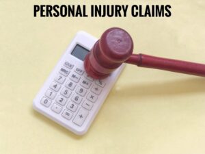 Personal Injury Claims wording with calculator and judge hammer on color paper view background